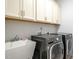Functional laundry room featuring overhead cabinets, utility sink and modern washer and dryer at 408 Torwood Cir, Apex, NC 27523
