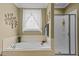 Bathroom featuring a soaking tub, a clear glass shower, and neutral-toned tile at 503 Fish Pond Ct, Rolesville, NC 27571