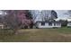 Quaint single-story home featuring white siding, dark shutters, and a blossoming magnolia tree in the front yard at 530 Broad Rd, Roxboro, NC 27573