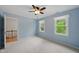 Bedroom with ceiling fan and two windows with views of mature trees and staircase at 5610 Frenchmans Creek Dr, Durham, NC 27713