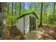 Storage shed with double doors nestled between mature trees in backyard at 5610 Frenchmans Creek Dr, Durham, NC 27713