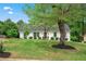 Charming white home featuring a lush, green lawn and mature trees under a bright blue sky at 5712 Wintergreen Dr, Raleigh, NC 27609