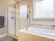 Bright bathroom features a shower, soaking tub, and decorative window at 65 N Wilders Ridge Way, Clayton, NC 27527