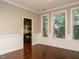 Dining room with hardwood floors, modern wainscoting, three windows, and view to the kitchen at 65 N Wilders Ridge Way, Clayton, NC 27527