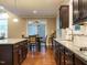 Spacious kitchen with dark cabinetry, granite counters, stainless sink, and hardwood flooring at 65 N Wilders Ridge Way, Clayton, NC 27527