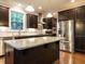 A modern kitchen with dark cabinets, stainless steel appliances, and a large island with granite countertops at 65 N Wilders Ridge Way, Clayton, NC 27527
