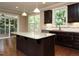 Kitchen with dark cabinets, granite countertops, stainless steel appliances and view to outdoor living at 65 N Wilders Ridge Way, Clayton, NC 27527