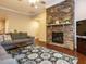 Living room with stone fireplace, hardwood floors, ceiling fan, and natural light at 65 N Wilders Ridge Way, Clayton, NC 27527