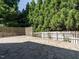 Stone patio area features white and stained fences, string lights, and mature trees for a cozy backyard setting at 65 N Wilders Ridge Way, Clayton, NC 27527