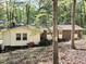 View of a charming single-story home with a brick facade, complemented by lush trees and greenery surrounding the property at 6709 Johnsdale Rd, Raleigh, NC 27615