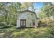Outbuilding nestled in the trees featuring a small porch and red framed glass doors at 6709 Johnsdale Rd, Raleigh, NC 27615