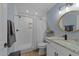 A well-lit bathroom showcases white tile shower, sleek fixtures, and a granite countertop vanity and modern round mirror at 703 E Horne St, Clayton, NC 27520