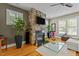 Warm living room featuring a stone fireplace, ceiling fan, hardwood floors, and plantation shutters at 714 Mordecai Towne Pl, Raleigh, NC 27604