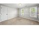 Bright bedroom with carpeting, two windows, and a door at 7705 Glenharden Dr, Raleigh, NC 27613