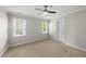 Bright bedroom features neutral paint, plush carpet, a ceiling fan, and natural light from two windows at 7705 Glenharden Dr, Raleigh, NC 27613