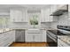 Modern kitchen with white cabinets, granite counters, stainless steel appliances, and subway tile backsplash at 7705 Glenharden Dr, Raleigh, NC 27613