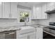 Updated kitchen with white cabinetry, granite countertops, stainless steel appliances, and stylish backsplash at 7705 Glenharden Dr, Raleigh, NC 27613