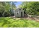 Charming outbuilding with a decorative star, enclosed by a wooden fence and surrounded by green grass and mature trees at 7705 Glenharden Dr, Raleigh, NC 27613