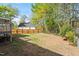 Large backyard featuring a wooden fence, grass, and mature trees on a sunny day at 807 Clean View Ct, Fuquay Varina, NC 27526