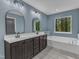 Well-lit bathroom features double vanity with dark cabinets and soaking tub with a wooded view at 858 Lake Artesia Ln, Fuquay Varina, NC 27526