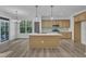 The open kitchen features an island, stainless steel appliances, wooden cabinets, and contemporary light fixtures at 858 Lake Artesia Ln, Fuquay Varina, NC 27526