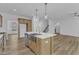 The kitchen features an island with a sink, stainless steel appliances, wooden cabinets, and contemporary light fixtures at 858 Lake Artesia Ln, Fuquay Varina, NC 27526