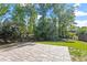 Green backyard featuring a brick patio, lush green grass, mature trees, and a classic black fence at 905 Moye Dr, Raleigh, NC 27606