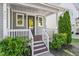 Inviting covered front porch with wood stairs and white railings, complemented by lush landscaping at 905 Moye Dr, Raleigh, NC 27606