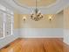 Dining area featuring a tray ceiling, elegant chandelier, wainscoting, and hardwood floors at 9220 Meadow Mist Ct, Raleigh, NC 27617