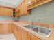 Close-up of a kitchenette showcasing wood cabinets, stainless steel sink, and tiled backsplash at 9220 Meadow Mist Ct, Raleigh, NC 27617