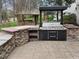 Stone surround outdoor kitchen with built-in grill, counters, and storage at 9220 Meadow Mist Ct, Raleigh, NC 27617