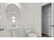 Well-lit powder room with a pedestal sink, round mirror, and convenient access to an organized closet at 4867 Pioneer Dr, Sanford, NC 27330
