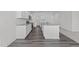 Modern kitchen with white cabinets, stainless steel appliances, a granite island, and gray wood flooring at 103 Gladstone Loop, Clayton, NC 27520