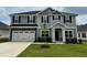 Two-story home with an attached two-car garage, a covered front porch, mature grass, and landscaped yard at 107 Southern Estates Dr, Sanford, NC 27330