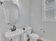 Modern powder room featuring a pedestal sink, round mirror, and a toilet with storage shelf at 1136 Remey Ave, Wake Forest, NC 27587