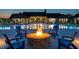 A fire pit and chairs sits near a beautiful pool and community clubhouse at twilight at 1636 Raven Falls Dr, Wendell, NC 27591