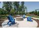 A communal fire pit surrounded by blue Adirondack chairs and mature trees at 1636 Raven Falls Dr, Wendell, NC 27591