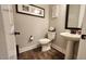 Cozy bathroom features pedestal sink, toilet, wall art and warm-toned walls and wood-look flooring at 1643 Wimberly Rd, Apex, NC 27523