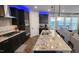 Open kitchen boasts dark cabinetry, a large granite island, stainless steel appliances, and modern pendant lighting at 1643 Wimberly Rd, Apex, NC 27523
