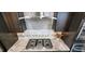 Close-up view of a gas cooktop with stainless steel hood, granite counters and elegant backsplash at 1643 Wimberly Rd, Apex, NC 27523