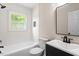 Bright bathroom features a shower-tub combo with white tiling and a window allowing natural light to fill the space at 2304 Nelson St, Raleigh, NC 27610