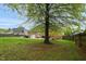 Large, grassy backyard featuring a brick home, patio, and a mature tree, perfect for outdoor activities and relaxation at 2326 Marlow Dr, Burlington, NC 27215