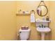 Cozy powder room featuring a pedestal sink, toilet, and decorative shelves against a yellow wall at 2326 Marlow Dr, Burlington, NC 27215