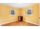 Bright bedroom with hardwood floors, two windows, a mini fridge, and light yellow walls at 2721 Thelma St, Durham, NC 27704