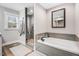 Bathroom features a shower with glass door, tub with gray tile surround, and natural light from the window at 305 E First St, Princeton, NC 27569