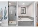 Well-lit bathroom showcases a gray-tiled shower with glass door and a tiled soaking tub with modern fixtures at 305 E First St, Princeton, NC 27569