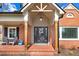 Inviting front porch with a brick floor, comfortable seating, and a decorative front door wreath at 305 E First St, Princeton, NC 27569