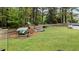 Expansive backyard with lush green lawn, a wooden play set, and privacy fence at 402 Green Turret Dr, Rolesville, NC 27571
