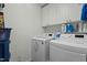 Well-organized laundry room with front load washer and dryer, storage cabinets, and laundry supplies at 402 Green Turret Dr, Rolesville, NC 27571