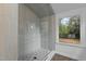 Walk-in shower features decorative tile surround, pebble tile floor, and a large picture window at 4812 Latimer Rd, Raleigh, NC 27609